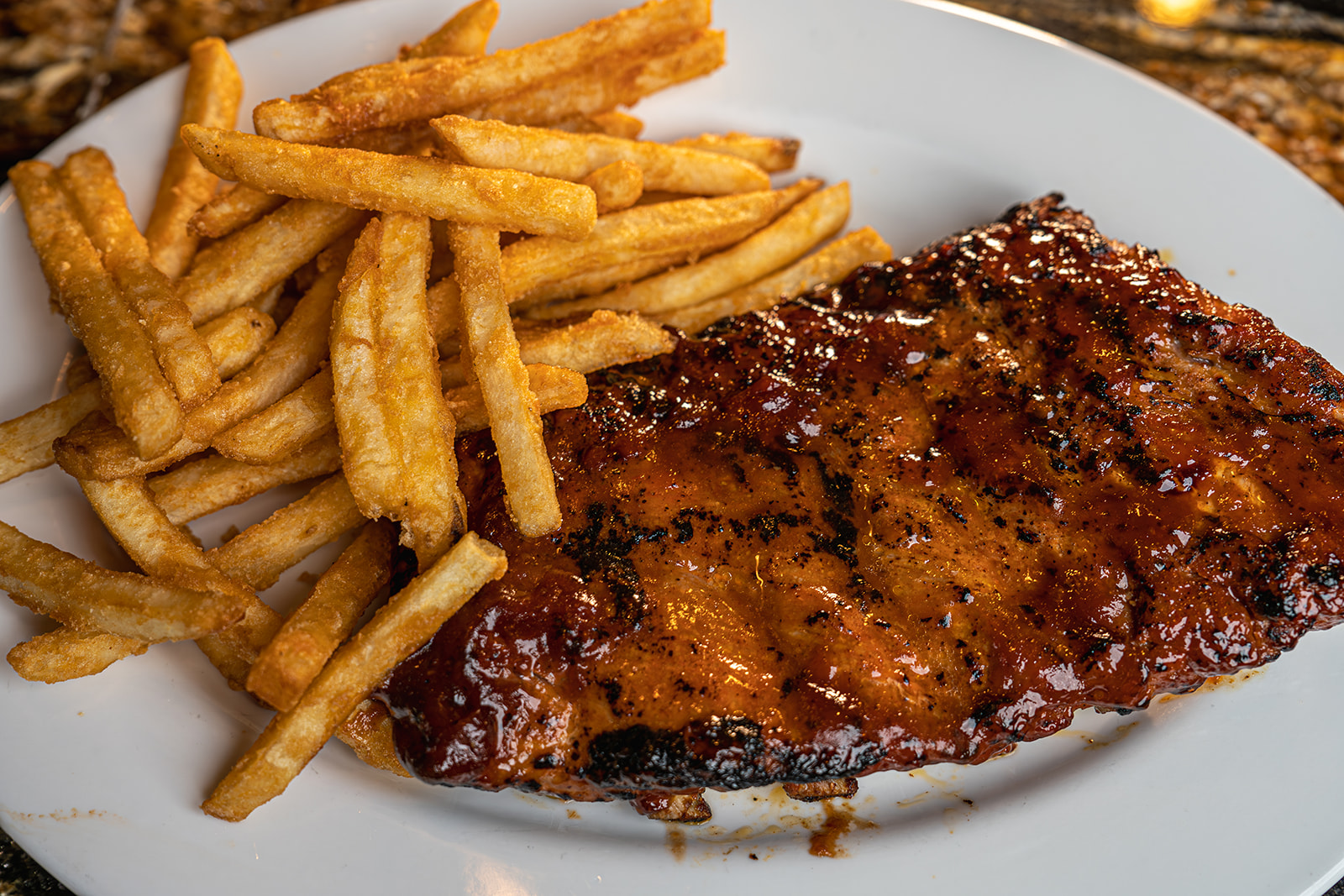 Baby back ribs with honey bourbon bbq sauce and a side of french fries by the 8th Street at the Ivy